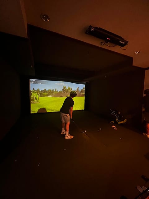 Golfer swinging in a simulator bay with the projector mounted on the ceiling