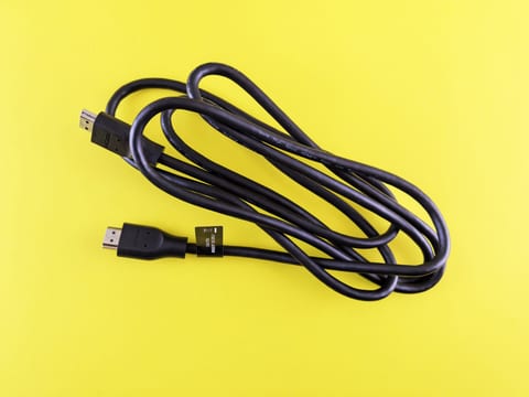 Coiled black HDMI cable on a yellow background